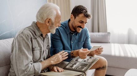 young_man_looking_at_old_photos_with_elderly_man